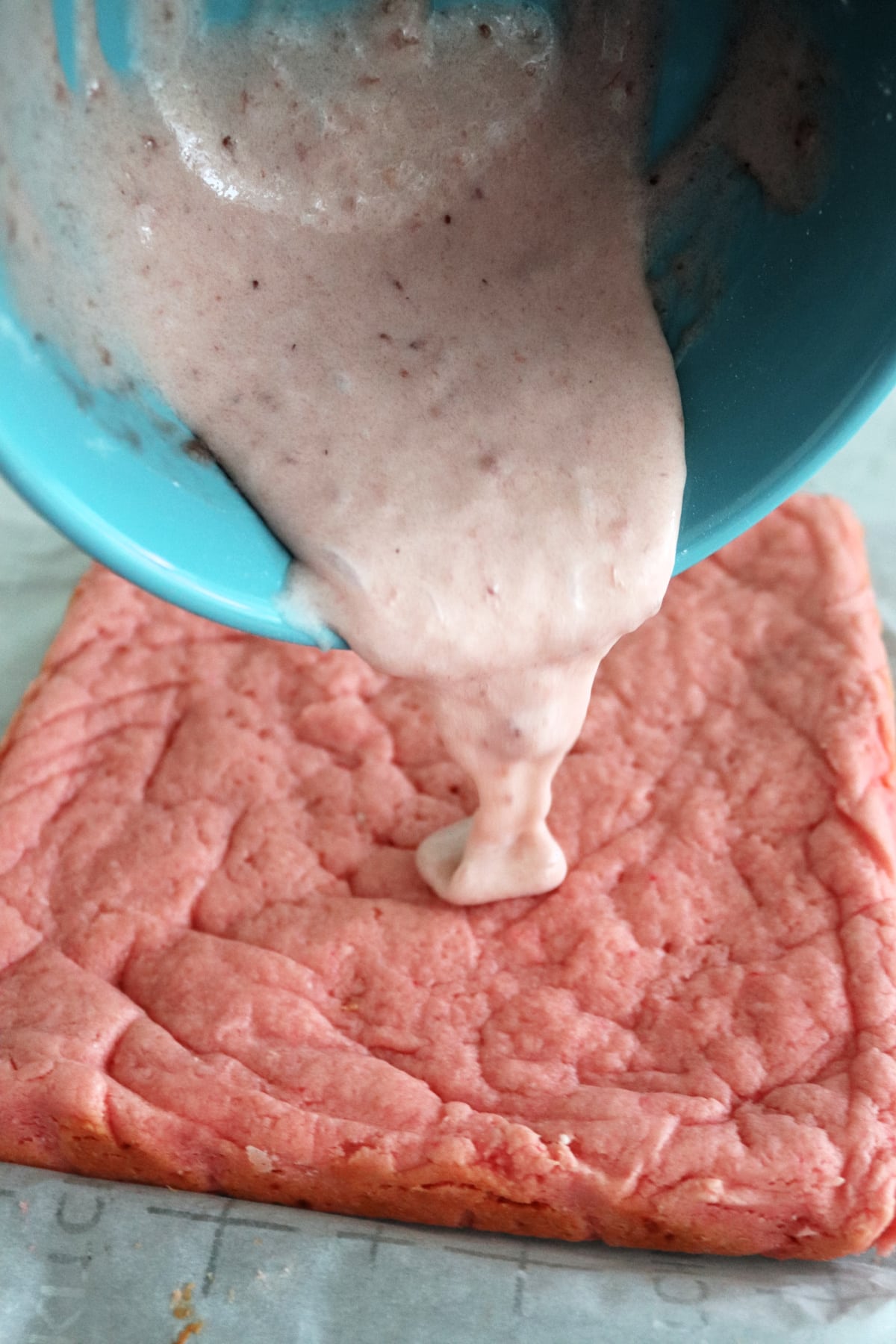 Strawberry glaze being poured onto strawberry bars.