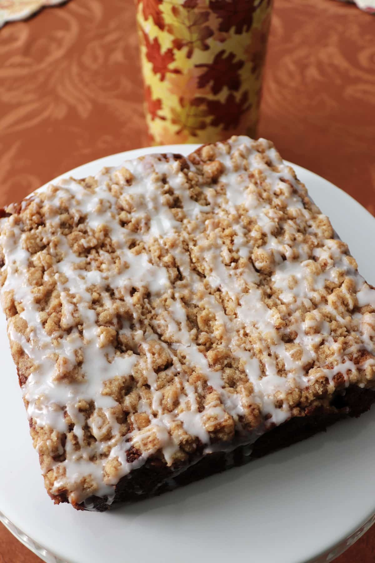Overhead view of a whole banana crumb cake on a white plate.