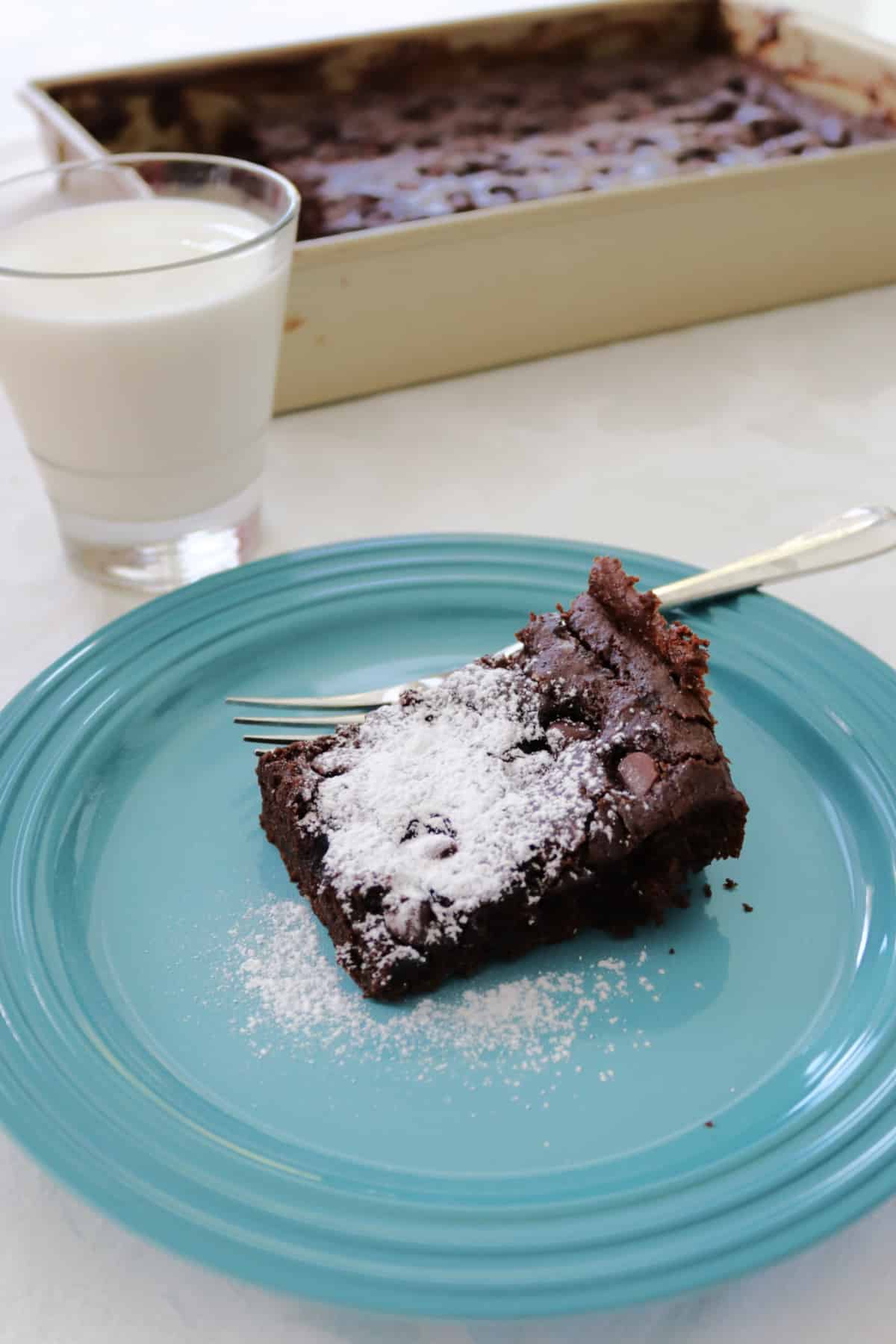 A slice of chocolate chip dump cake dusted with powdered sugar.
