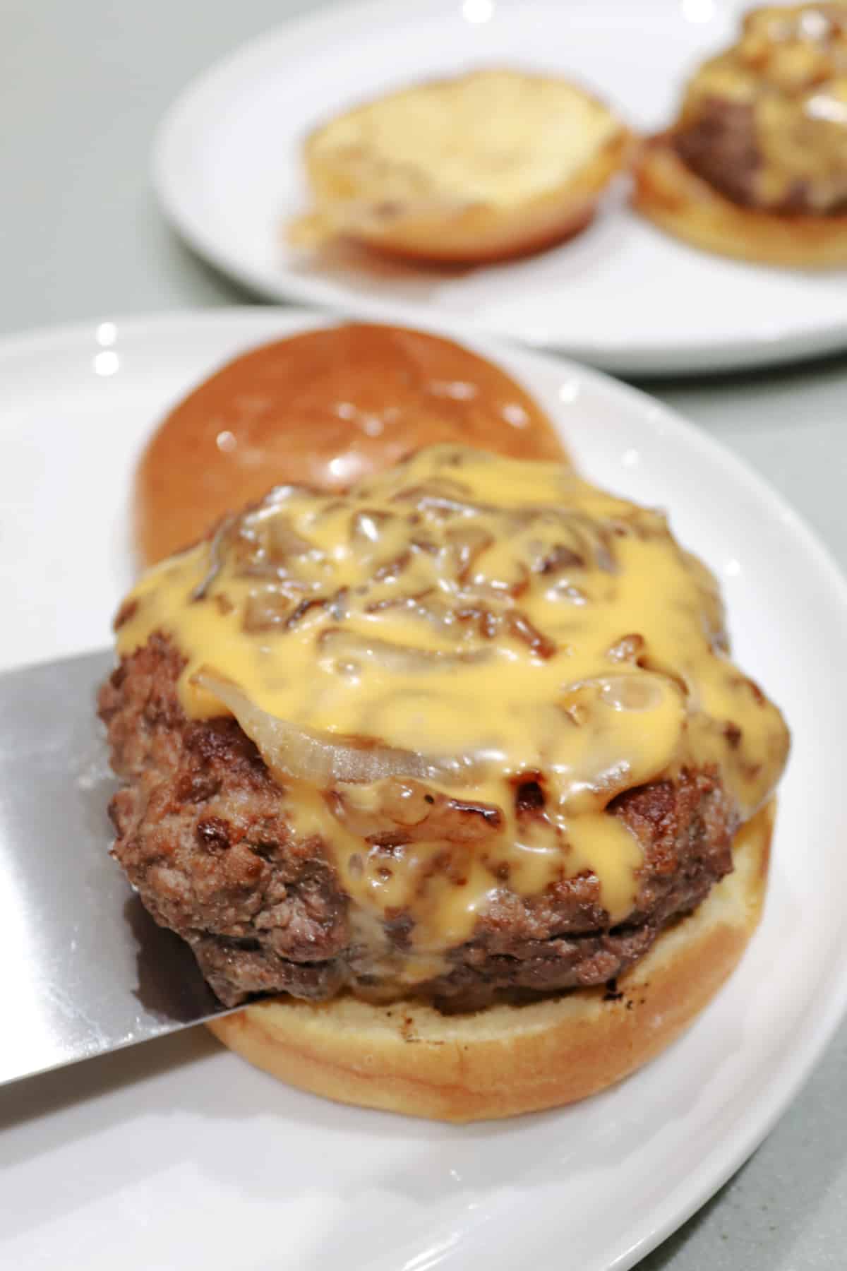 Two butter burgers on white plates.
