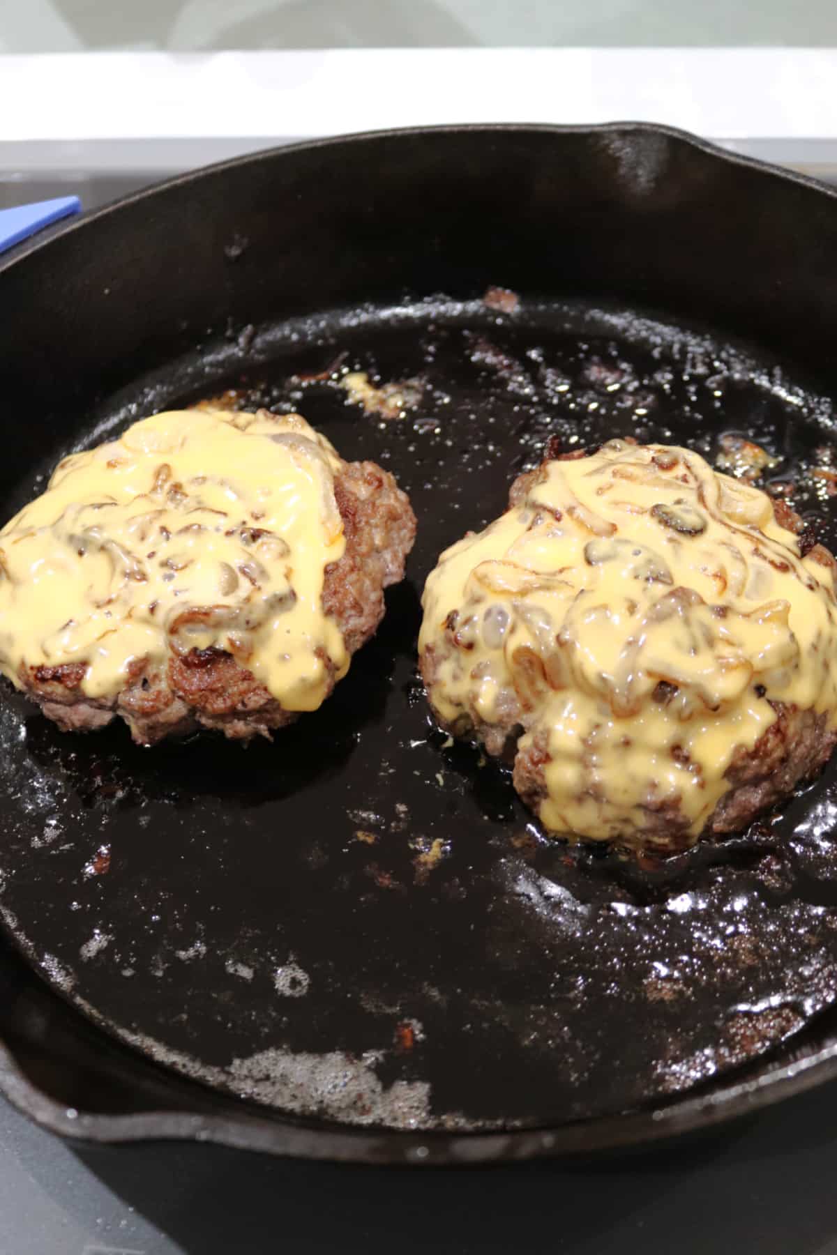 Two butter burgers in a cast iron skillet.