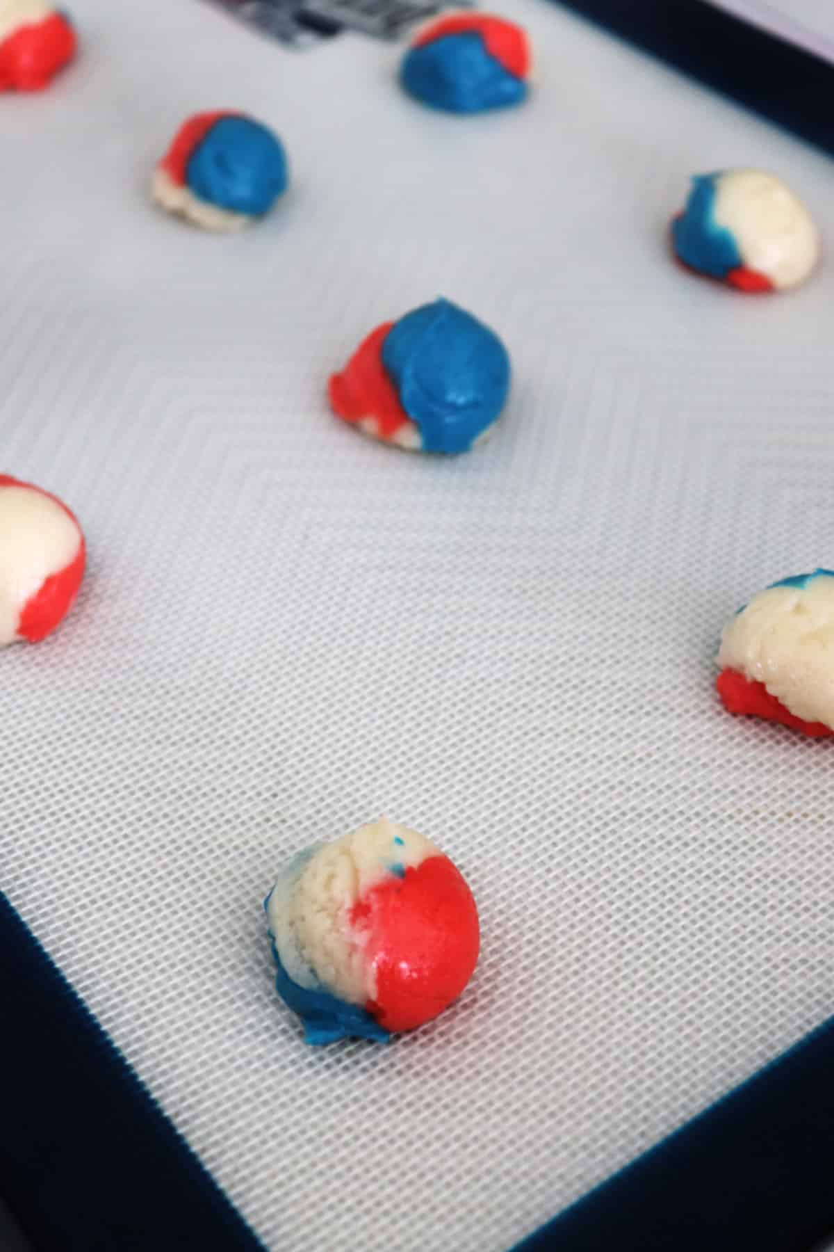 Red, white, and blue cookie dough on a baking sheet.