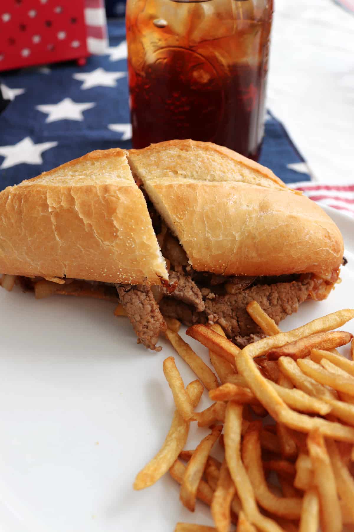 A steak sandwich on a plate with french fries.