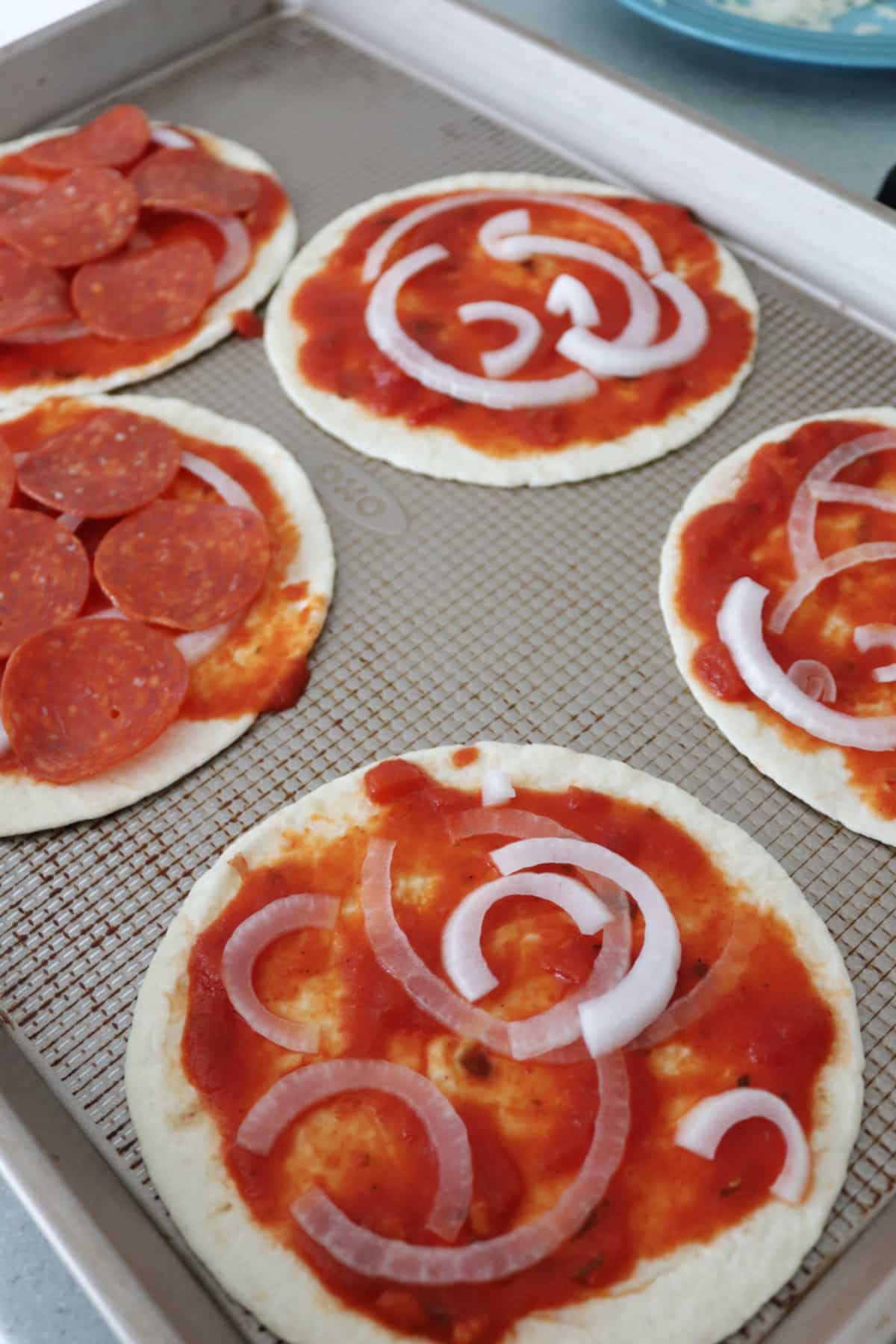 Tortilla pizzas on a baking sheet ready to go in the oven.