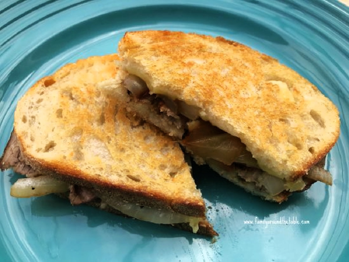 Roast beef brie caramelized onion grilled cheese sandwich on a blue plate.