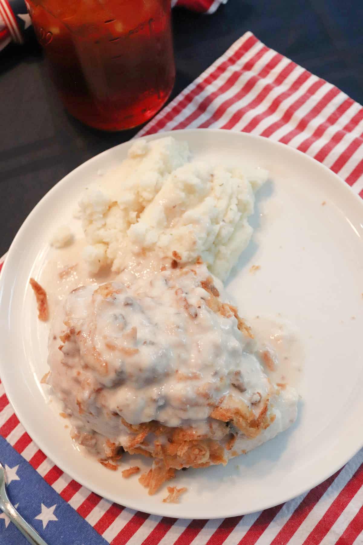 Overhead view of Lazy Chicken on a white plate next to mashed potatoes.