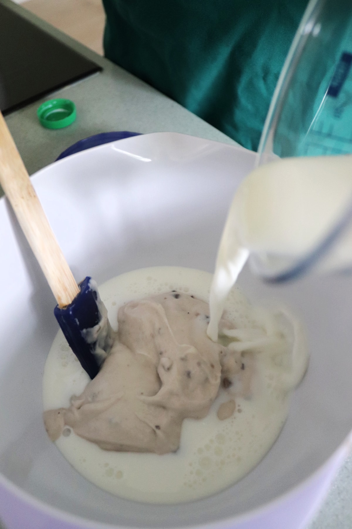 Milk being poured into a bowl with condensed cream of mushroom soup.